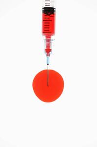 Hypodermic needle filled with red liquid.