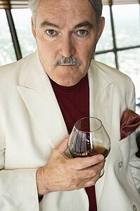 Senior man in suit holding snifter of brandy