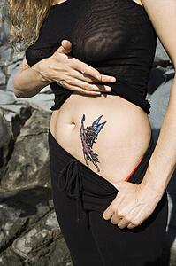 Woman revealing tattoo of fairy on stomach