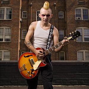 Punk playing guitar with building in background