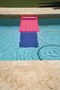 Pink float and vacuum hose in swimming pool.