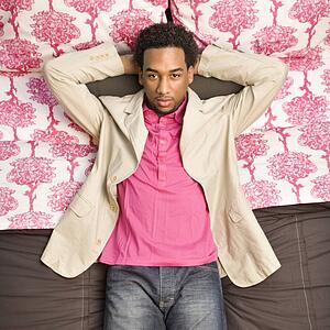 Young man laying on bed looking at viewer.