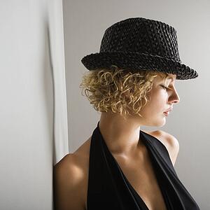 Profile of young adult woman wearing fedora hat with eyes closed