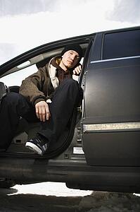 Confident male teenager sitting in car