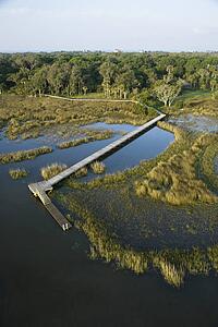 Aerial view of dock and boardwalk stretching over coastal marsh area on Bald Head Island, North Carolina.