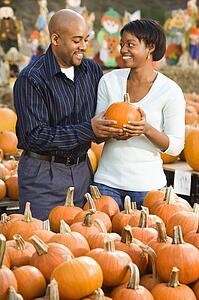 Couple picking out pumpkins and smiling at outdoor market