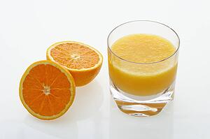 Halved orange and glass of orange juice on white background.