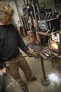 Metal-smith heating metal in forge
