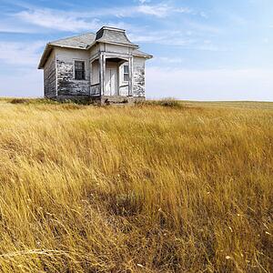 Weathered abandoned building in remote grassland.