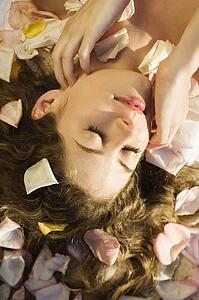 Above view of Caucasian mid-adult woman lying down with hair spread out on rose petals. 