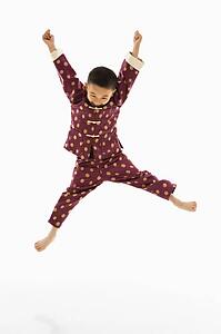 Boy in traditional attire jumping into air excitedly against white background