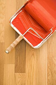 Still life of paint roller in tray on wood floor