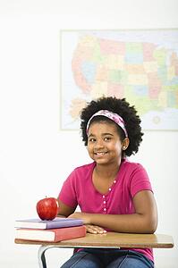 African American girl sitting in school desk smiling at viewer.