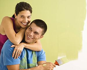 Happy smiling couple painting interior wall of home