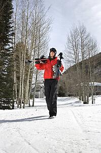 Teenager walking and carrying skis