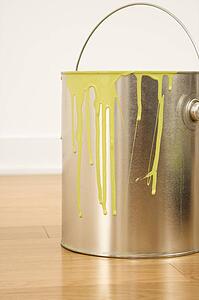 Paint can with drips sitting on wood floor