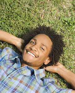 Lying in grass smiling with hands behind head