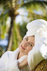 Caucasian mid-adult woman wearing robe with towel on head relaxing in tropical place.