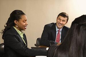 Businesspeople sitting at conference table talking and smiling
