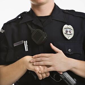 Close up of mid adult female Caucasian law enforcement officer with hands on gun.