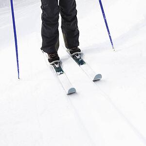 Skier legs, boots, poles and skis standing on slope