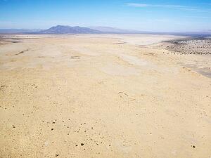 Aerial view of remote California desert with mountain range in background