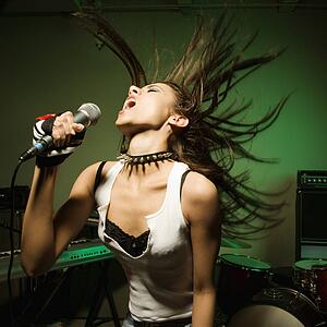 Female swinging head and hair while singing into microphone