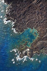 Aerial of Pacific ocean and Maui, Hawaii coast with lava rocks.