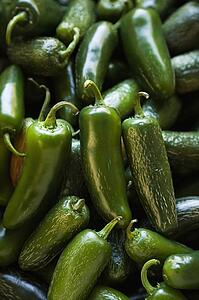 Pile of green jalapeno peppers at produce market.