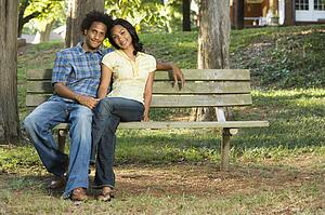 Happy smiling couple sitting on park bench together