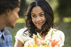 Woman holding flower bouquet smiling at man