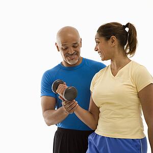 man assisting woman with dumbbells