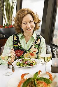 Caucasian mature woman with meal in restaurant smiling.