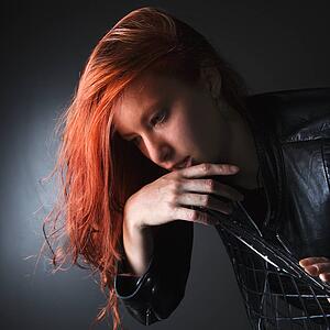 Pretty redhead young woman wearing leather jacket hanging over back of chair