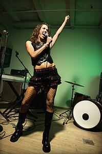 Caucasian female singning into microphone.