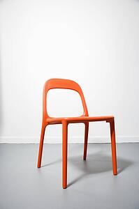 An orange modern chair with a white background.