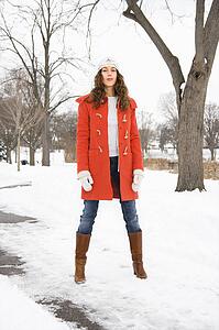 Caucasian young adult female looking at viewer and standing in snow covered street.