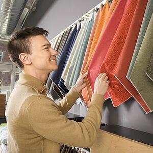 Young man looking at fabric swatches in retail store.