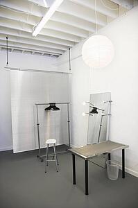 Workspace with table, chair, mirror, clothing rack and room divider.