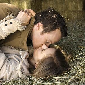 Couple lying down in hay kissing
