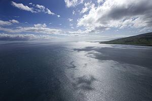 Pacific ocean and sky with clouds and corner of island in Hawaii