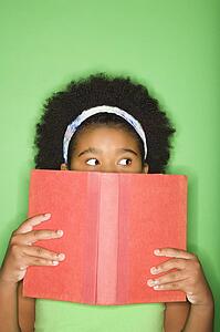 Girl with book held up to face looking suspiciously to the side