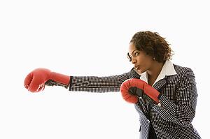 Businesswoman wearing boxing gloves punching