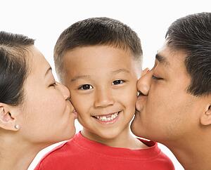 Mother and father kissing opposite cheeks of smiling son