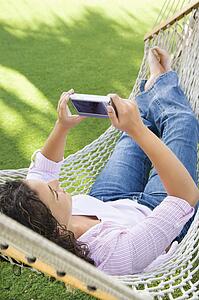 Woman lying in hammock using PDA