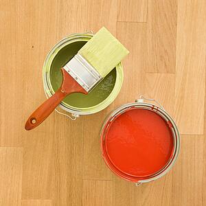 Paintbrush with paint cans on wood floor