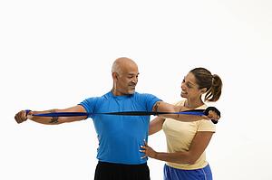 Woman assisting man with stretching band