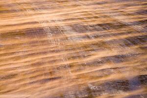 Close up of ice covered road with tire marks.