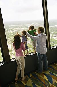 Caucasian family looking out observation deck at Tower of the Americas in San Antonio, Texas.