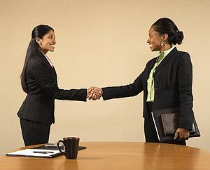 Businesswomen in suits shaking hands 